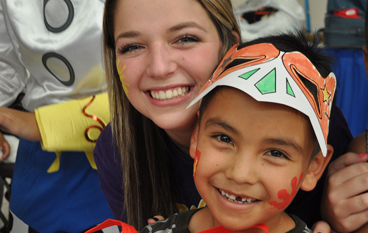 Member of the youth ministry tean brings a smile to a young child